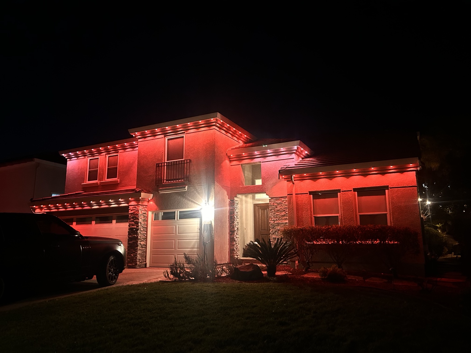 Home lit in red and gold game-day permanent lighting at night