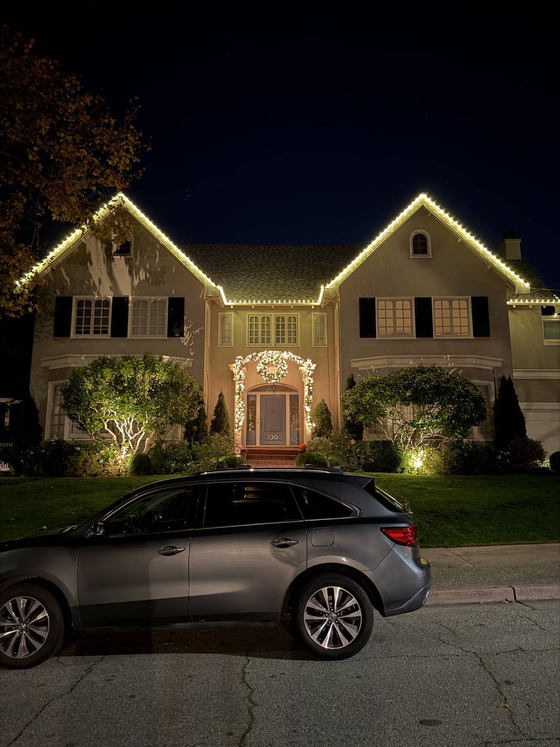 Traditional two-story home with classic warm white Christmas lighting, wreaths and garland